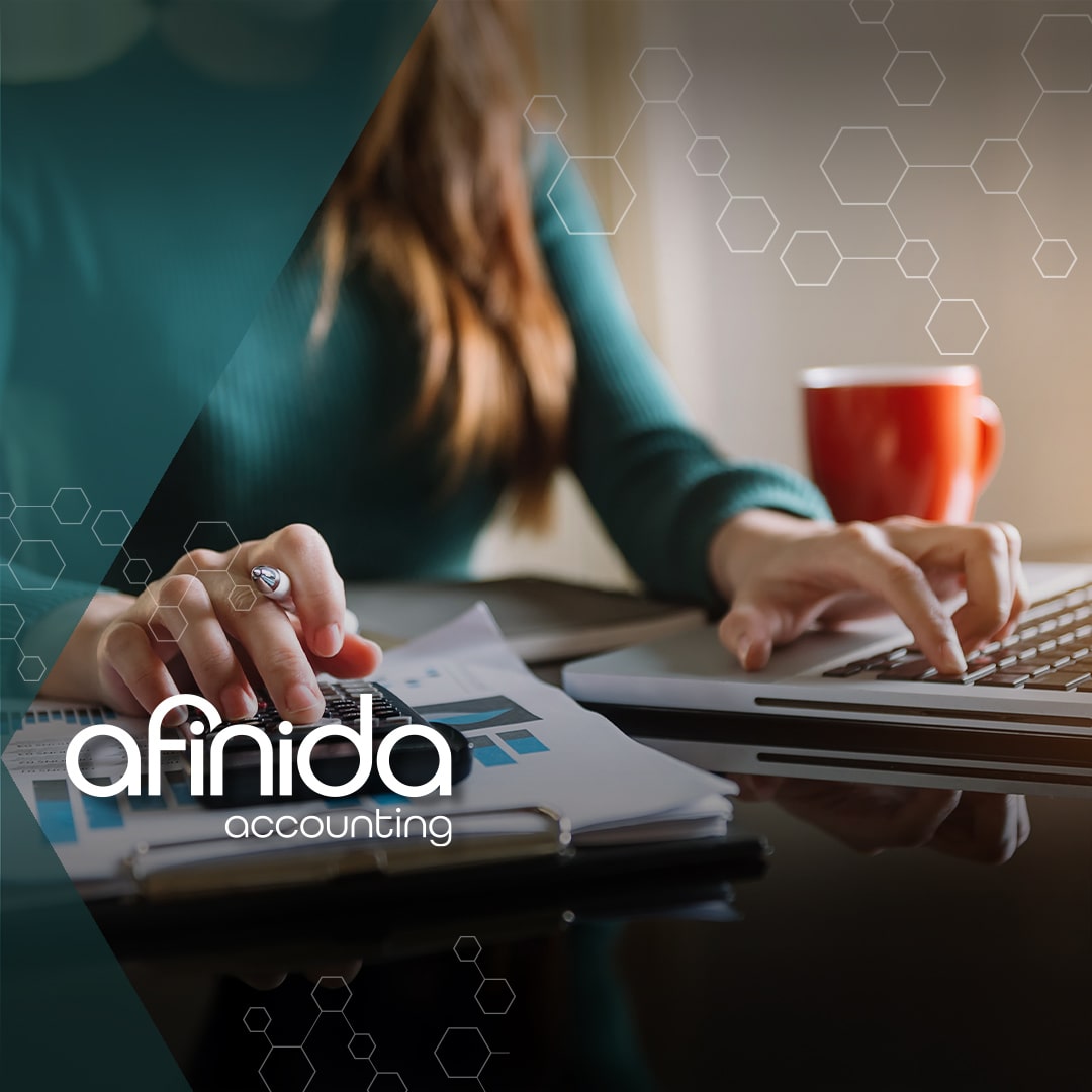 A professional working on financial reports with a calculator and laptop, representing Afinida Accounting’s expert services for growing businesses.