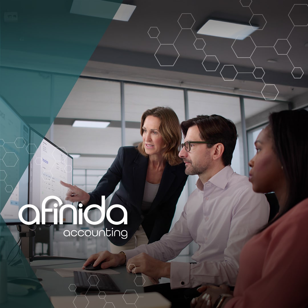 Three professionals review financial data on a screen in a modern office, discussing San Diego business accounting solutions