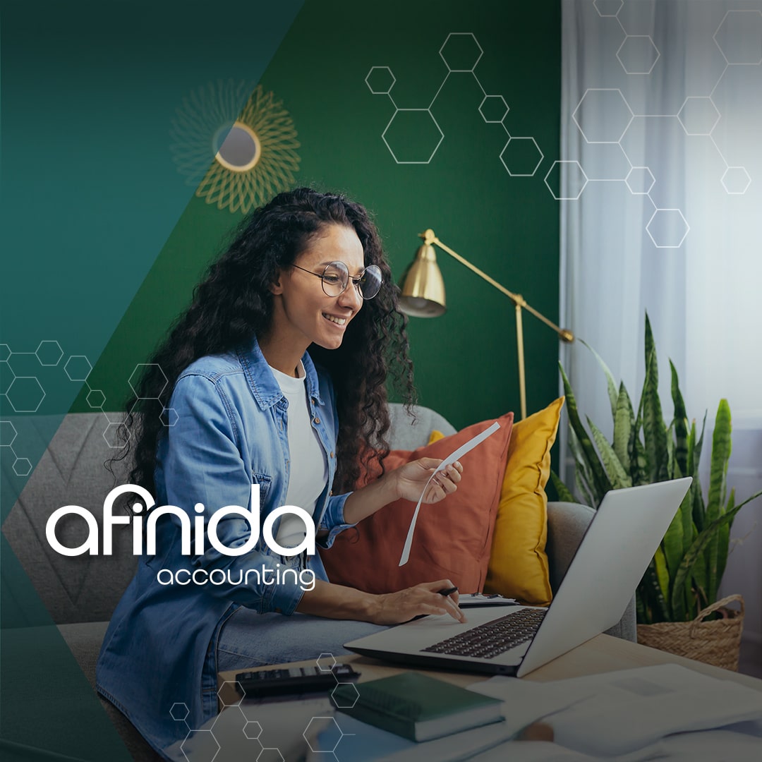 Woman smiles while reviewing documents and using a laptop, working with expert accounting support for small business financial management.