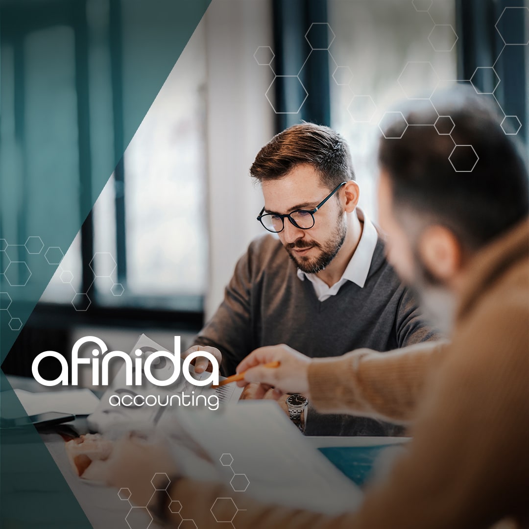 Accountant at Afinida reviewing financial reports with a small business owner and afinida accounting logo displayed